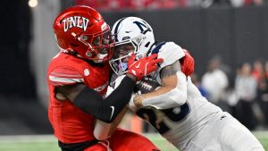 Nevada running back Ashton Hayes, right, is stopped by UNLV defensive back Jett Elad, left, during the first half of an NCAA college football game Saturday, Nov. 30, 2024, in Las Vegas. (David Becker/AP Photo)