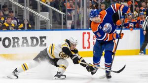 Boston Bruins' Nikita Zadorov (91) and Edmonton Oilers' Evan Bouchard (2) battle for the puck during second period NHL action in Edmonton on Thursday, December 19, 2024. (Timothy Matwey/AP)