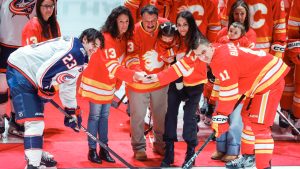 Columbus Blue Jackets' Sean Monahan, left, and Calgary Flames' Mikael Backlund join the family of Johnny Gaudreau at centre ice prior to first period NHL hockey action in Calgary on Tuesday, Dec. 3, 2024. (Jeff McIntosh/CP)