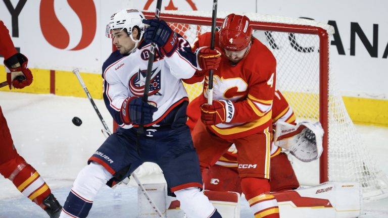 Columbus Blue Jackets' Sean Monahan, left, is checked by Calgary Flames' Rasmus Andersson during first period NHL hockey action in Calgary on Tuesday, Dec. 3, 2024. (Jeff McIntosh/THE CANADIAN PRESS)