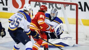 St. Louis Blues goalie Jordan Binnington, right, blocks the net on Calgary Flames' Blake Coleman, centre, as Colton Parayko checks during second period NHL hockey action in Calgary on Thursday, Dec. 5, 2024. (Jeff McIntosh/CP)