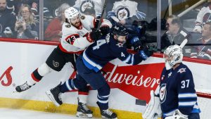 Winnipeg Jets' Neal Pionk (4) and Ottawa Senators' Noah Gregor (73) collide behind Jets goaltender Connor Hellebuyck (37) during first period NHL action in Winnipeg on Saturday, December 28, 2024. (John Woods/CP)