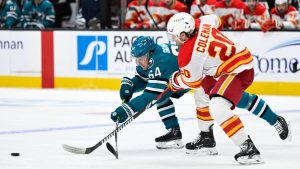 San Jose Sharks center Mikael Granlund (64) and Calgary Flames center Blake Coleman (20) attempt to reach the puck during the second period of an NHL hockey game Saturday, Dec. 28, 2024, in San Jose, Calif. (Eakin Howard/AP)