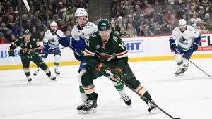 Minnesota Wild center Joel Eriksson Ek (14) skates to the puck past of Vancouver Canucks defenseman Quinn Hughes (43) during the first period of an NHL hockey game Tuesday, Dec. 3, 2024, in St. Paul, Minn. (Craig Lassig/AP)