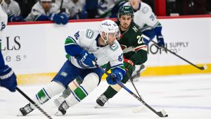 Vancouver Canucks centre Max Sasson, left, skates past Minnesota Wild center Marat Khusnutdinov during the first period of an NHL hockey game Tuesday, Dec. 3, 2024, in St. Paul, Minn. (Craig Lassig/AP)