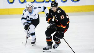 Utah Hockey Club's Clayton Keller, left, and Calgary Flames' Mikael Backlund chase the puck during third period NHL hockey action in Calgary, Alta., Thursday, Jan. 2, 2025. THE CANADIAN PRESS/Jeff McIntosh