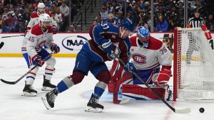 Colorado Avalanche center Casey Mittelstadt, front, collects the puck as Montreal Canadiens defenseman Alexandre Carrier, back left, and goaltender Jakub Dobes defend in the first period of an NHL hockey game Saturday, Jan. 4, 2025, in Denver. (AP Photo/David Zalubowski)