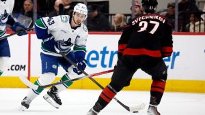 Vancouver Canucks' Quinn Hughes (43) controls the puck in front of Carolina Hurricanes' Andrei Svechnikov (37) during the first period of an NHL hockey game in Raleigh, N.C., Friday, Jan. 10, 2025. (AP Photo/Karl DeBlaker)