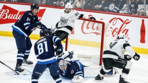 Winnipeg Jets goaltender Eric Comrie (1) goes down to save the shot from Los Angeles Kings' Phillip Danault (24) during first period NHL action in Winnipeg on Friday, January 10, 2025. THE CANADIAN PRESS/John Woods