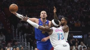 Denver Nuggets center Nikola Jokic, left, passes as Miami Heat center Bam Adebayo (13) defends during the first half of an NBA basketball game, Friday, Jan. 17, 2025, in Miami. (AP Photo/Lynne Sladky)