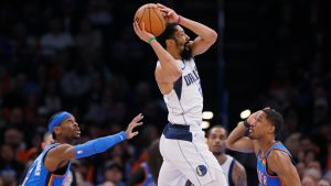 Dallas Mavericks guard Spencer Dinwiddie, center, looks to pass the ball away from Oklahoma City Thunder guards Shai Gilgeous-Alexander, left, and Aaron Wiggins, right, during an NBA game Thursday, Jan. 23, 2025. (AP Photo/Nate Billings)