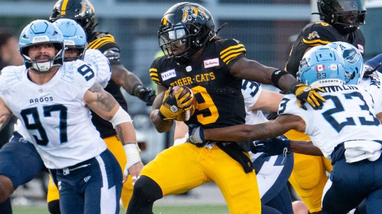 Hamilton Tiger Cats running back James Butler breaks through the defensive line of the Toronto Argonauts during CFL football game action in Hamilton, Ont. on Saturday, July 20, 2024. (CP/Peter Power)