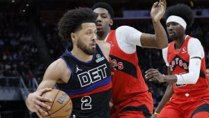 Detroit Pistons guard Cade Cunningham (2) drives to the basket against Toronto Raptors guard RJ Barrett (9) and forward Chris Boucher (25) during the first half of an NBA basketball game Saturday, Jan. 11, 2025, in Detroit. (Duane Burleson/AP)