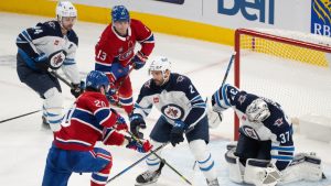 Winnipeg Jets goaltender Connor Hellebuyck (37) stops Montreal Canadiens' Juraj Slafkovsky (20) as Winnipeg Jets' Dylan DeMelo (2) defends during second period NHL hockey action in Montreal on Tuesday, Jan. 28, 2025. (Christinne Muschi/CP)