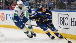 Vancouver Canucks' Phillip Di Giuseppe (34) battles St. Louis Blues' Tyler Tucker (75) for the puck during the first period of an NHL hockey game Monday, Jan. 27, 2025, in St. Louis. (Joe Puetz/AP)