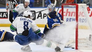 Vancouver Canucks' Conor Garland (8) scores past St. Louis Blues goaltender Jordan Binnington (50) during the first period of an NHL hockey game Monday, Jan. 27, 2025, in St. Louis. (Joe Puetz/AP)