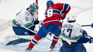 Montreal Canadiens' Lane Hutson (48) is stopped by Vancouver Canucks goaltender Kevin Lankinen (32) as teammate Noah Juulsen (47) moves in to defend during first period NHL hockey action in Montreal, Monday, Jan. 6, 2025. (Ryan Remiorz/CP)