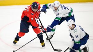 Washington Capitals right wing Tom Wilson (43) gets his stick caught in the jersey of Vancouver Canucks right wing Conor Garland (8) during overtime of an NHL hockey game, Wednesday, Jan. 8, 2025, in Washington. The Capitals won 2-1 in overtime. (Nick Wass/AP)