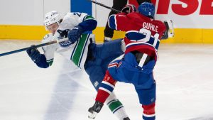 Vancouver Canucks Jonathan Lekkerimaki, left, is checked by Montreal Canadiens defenceman Kaiden Guhle (21) during first period NHL hockey action in Montreal, Monday, Jan. 6, 2025. (Ryan Remiorz/CP)