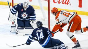 Winnipeg Jets goaltender Connor Hellebuyck (37) saves the shot from Anaheim Ducks' Ross Johnston (44) as Ville Heinola (14) defends during first period NHL action. (John Woods/CP)