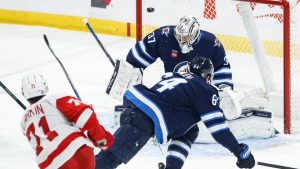 Detroit Red Wings' Dylan Larkin (71) scores on Winnipeg Jets goaltender Connor Hellebuyck (37) during first period NHL action in Winnipeg. (John Woods/CP)