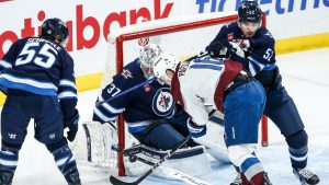 Winnipeg Jets goaltender Connor Hellebuyck (37) saves the shot as Dylan Coghlan (52) defends against Colorado Avalanche's Juuso Parssinen (16) during second period NHL action in Winnipeg on Saturday, January 11, 2025. (John Woods/CP)