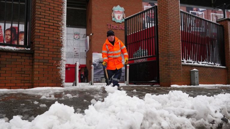 A worker clears snow from a sidewalk in front of the stadium of the premier league soccer club FC Liverpool in Liverpool, England, Sunday, Jan. 5, 2025. (Peter Byrne/PA via AP)