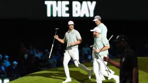 The Bay Golf Club's Wyndham Clark, left, and teammates Ludvig Aberg, top, and Shane Lowry celebrate winning the third hole during the inaugural match of the TMRW Golf League, Tuesday, Jan. 7, 2025, in Palm Beach Gardens, Fla. TGL features six teams of four players competing against each other in a tech-infused arena the size of a football field. (AP Photo/Rebecca Blackwell)