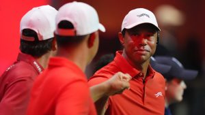 Tiger Woods of Jupiter Links Golf Club bumps fists with teammates Kevin Kisner, left, and Tom Kim as the team is introduced during a match of the TMRW Golf League (TGL) against Boston Common Golf, Monday, Jan. 27, 2025, in Palm Beach Gardens, Fla. (Rebecca Blackwell/AP)