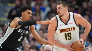 Denver Nuggets center Nikola Jokic, right, looks to pass the ball as San Antonio Spurs center Victor Wembanyama defends in the second half of an NBA basketball game. (David Zalubowski/AP)