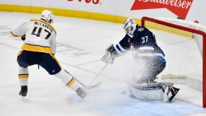 Winnipeg Jets goaltender Connor Hellebuyck (37) makes a save on Nashville Predators' Michael McCarron (47) during the first period of their NHL hockey game in Winnipeg, Tuesday, Jan. 7, 2025. (Fred Greenslade/CP)