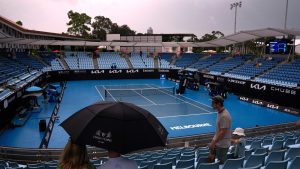 Spectators wait under umbrellas as rain suspends play during first-round matches at the Australian Open tennis championship in Melbourne, Australia, Sunday, Jan. 12, 2025.(Manish Swarup/AP)