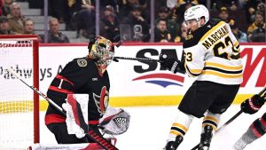 Boston Bruins' Brad Marchand (63) tries to get his stick on the puck as it bounces near the mask of Ottawa Senators goaltender Leevi Merilainen (1) during first period NHL hockey action in Ottawa, on Saturday, Jan. 18, 2025. (Justin Tang/CP)