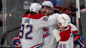 Montreal Canadiens right wing Patrik Laine (92) and defenceman Alexandre Carrier (45) hug right wing Josh Anderson, centre, after Anderson scored a goal, during the third period of an NHL hockey game against Utah Hockey Club, Tuesday, Jan. 14, 2025, in Salt Lake City. (Rick Egan/AP Photo)