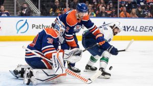 Vancouver Canucks' Conor Garland (8) and Edmonton Oilers' Evan Bouchard (2) battle in front as goalie Calvin Pickard (30) makes the save during third period NHL action in Edmonton on Thursday, January 23, 2025. (Jason Franson/CP)