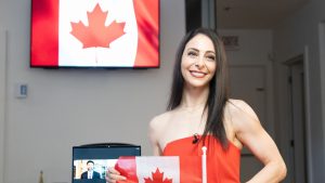 Pairs figure skater Deanna Stellato-Dudek poses with a flag after becoming a Canadian citizen in Montreal on Wednesday, Dec. 11, 2024. (Christinne Muschi/CP)