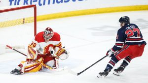 Calgary Flames goaltender Dustin Wolf (32) stops the shot from Winnipeg Jets' Nikolaj Ehlers (27) during first period NHL action in Winnipeg on Saturday, January 18, 2025. (John Woods/THE CANADIAN PRESS)