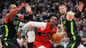 Toronto Raptors' RJ Barrett (9) drives between Boston Celtics' Al Horford (left) and Kristaps Porzingis (right) during first half NBA basketball action in Toronto on Wednesday, January 15, 2025. (Frank Gunn/THE CANADIAN PRESS)