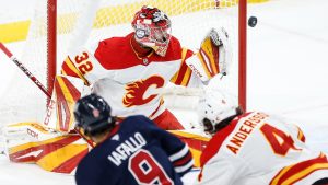 Winnipeg Jets' Alex Iafallo's (9) shot goes wide of Calgary Flames goaltender Dustin Wolf (32) as Rasmus Andersson (4) defends during third period NHL action in Winnipeg on Saturday, January 18, 2025. (John Woods/THE CANADIAN PRESS)