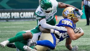 Winnipeg Blue Bombers receiver Drew Wolitarsky (82) is tackled by Saskatchewan Roughriders defenders during the first half of preseason CFL football action in Regina, Monday, May 20, 2024. (Heywood Yu/CP)