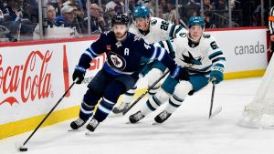 Winnipeg Jets' Josh Morrissey (44) carries the puck around San Jose Sharks' Jack Thompson (26) and Collin Graf (51) during second period NHL hockey action in Winnipeg, Monday, Feb. 24, 2025. (/Fred Greenslade/CP)