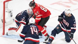 Canada's Sidney Crosby (87) battles for a rebound in front of United States goaltender Connor Hellebuyck (37) as Brock Faber (14) and Jaccob Slavin (74) defend during third period 4 Nations Face-Off hockey action. (Christinne Muschi/CP)