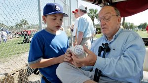 Former Major League Baseball Commissioner Fay Vincent signs an autograph for Louis Carrons, 12, of Rancho Cucamonga, Calif., during Los Angeles Dodgers baseball spring training in Vero Beach, Fla., March 1, 2006. (Richard Drew/AP)