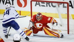 Toronto Maple Leafs' Auston Matthews, left, tries to get the puck past Calgary Flames goalie Dustin Wolf during third period NHL hockey action in Calgary on Tuesday, Feb. 4, 2025. (Jeff McIntosh/CP)